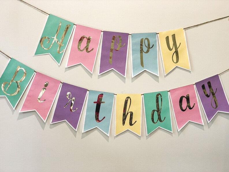 Pu&ograve; includere: Uno striscione color pastello con lettere dorate in foglia d'oro che compongono la scritta "Happy Birthday".