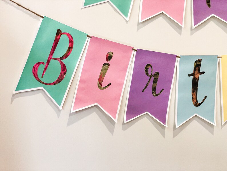 Pu&ograve; includere: Uno striscione colorato con la parola "Birthday" scritta in lettere dorate. Ogni lettera &egrave; su un pennone separato, con i colori che si alternano tra verde acqua, rosa, viola e azzurro.