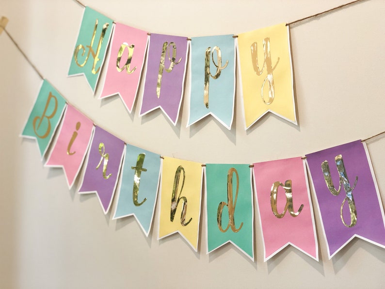 Pu&ograve; includere: Uno striscione color pastello con lettere dorate in foglia d'oro che compongono la scritta "Happy Birthday".