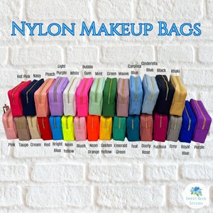 May include: A row of 20 nylon makeup bags in various colours, including hot pink, navy, peach, purple, white, gum, mint, green, mauve, blue, black, khaki, pink, taupe, cream, red, bright blue, neon yellow, blush, neon orange, golden yellow, emerald green, teal, dusty rose, fuchsia, grey, royal blue, and purple. The bags are arranged in two rows, with the top row labelled with the colour names and the bottom row labelled with the colour names and additional details.