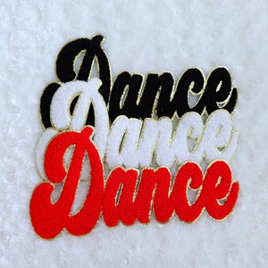 May include: Three embroidered patches spelling "Dance" in a cursive font. The patches are black, white, and red, each with a gold border. The patches are stacked on top of each other.