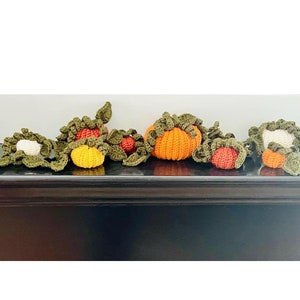 May include: A crocheted garland of pumpkins and leaves in shades of green, orange, and white. The garland is perfect for fall decor.