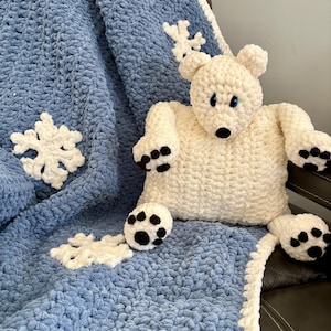 May include: A blue and white crocheted blanket with snowflake designs and a white crocheted polar bear with black paw prints.