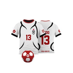 K&ouml;nnte beinhalten: Wei&szlig;es Fu&szlig;balltrikot mit roten Akzenten und der Nummer 13. Das Trikot hat schwarze geschwungene Linien und ein japanisches Flaggenemblem. Ein rot-wei&szlig;er Fu&szlig;ball liegt vor dem Trikot.