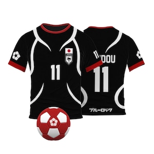 May include: Black soccer jersey with white accents and the number 11 on the front. The jersey has the Japanese flag and the words "JAPAN JFA" on the chest. The back of the jersey has the number 11 and the word "DOU" on the collar. The jersey is next to a red and white soccer ball.