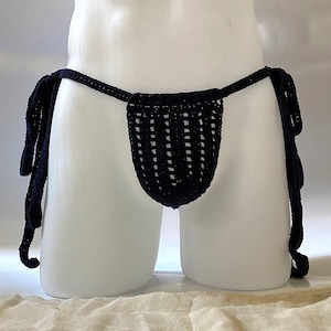 May include: A black crocheted garment with long ties. The garment is designed to be worn as underwear.