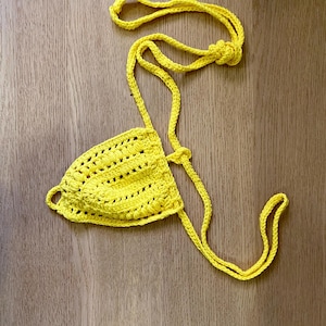 Può includere: Top bikini all'uncinetto giallo brillante con spalline regolabili. Il top presenta un design strutturato a trama aperta. Le cinghie sono annodate sulla schiena e intorno al collo. Il top del bikini è realizzato con un filato morbido e leggero.