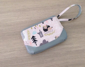 Puede incluir: Una pequeña bolsa de cremallera rosa y gris con asa. La bolsa tiene un estampado de bosque caprichoso con erizos, árboles y nubes.
