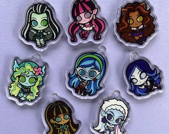 Könnte beinhalten: Acht bunte Charakter-Anhänger mit verschiedenen Monster High-Charakteren. Die Anhänger sind aus klarem Kunststoff mit schwarzem Umriss und an Schlüsselringen befestigt.