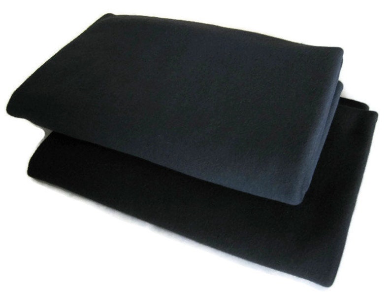 May include: Two black fleece blankets stacked on top of each other.