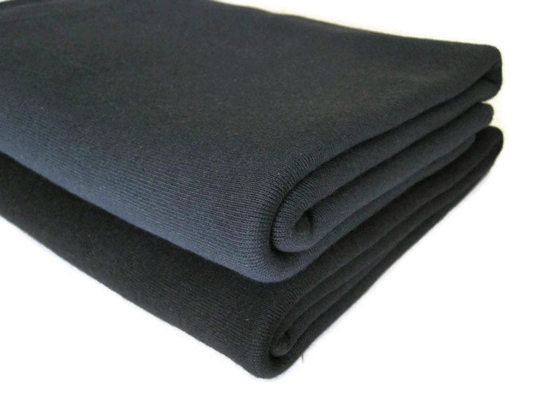 May include: Two folded pieces of black fabric. The fabric is soft and has a smooth texture.