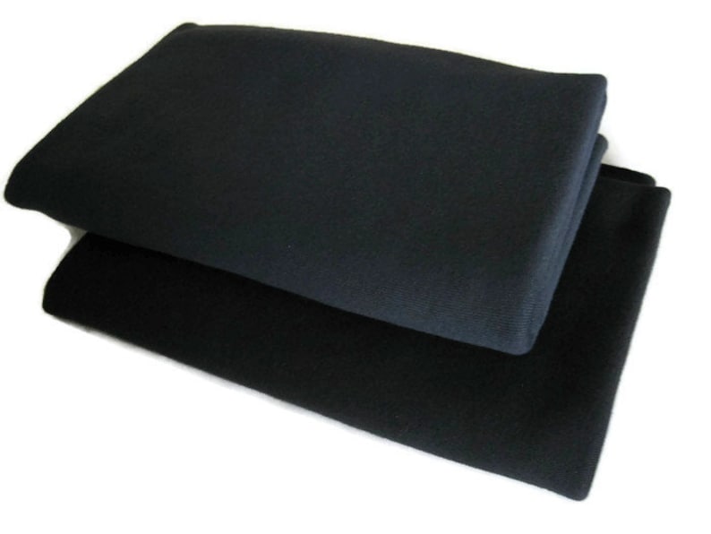 May include: Two black fabric squares stacked on top of each other. The top square is slightly larger than the bottom square.
