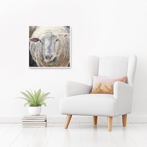 May include: A close-up painting of a white sheep's face. The sheep has a soft, fluffy coat and is looking directly at the viewer. The painting is done in a realistic style and captures the sheep's gentle expression.
