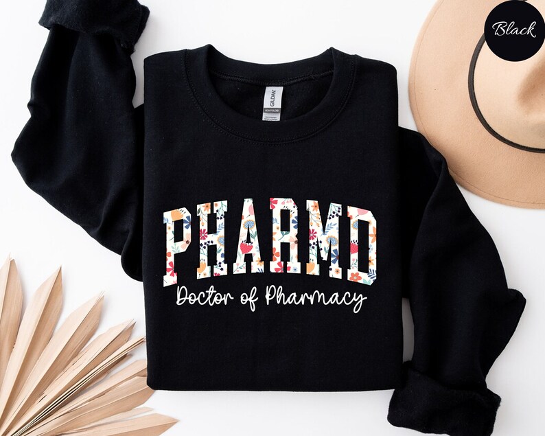 May include: Black sweatshirt with a floral design that says "PHARM.D. Doctor of Pharmacy"