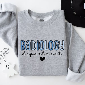 May include: A gray sweatshirt with the text "Radiology department" in blue and black lettering. A small black heart is below the text.
