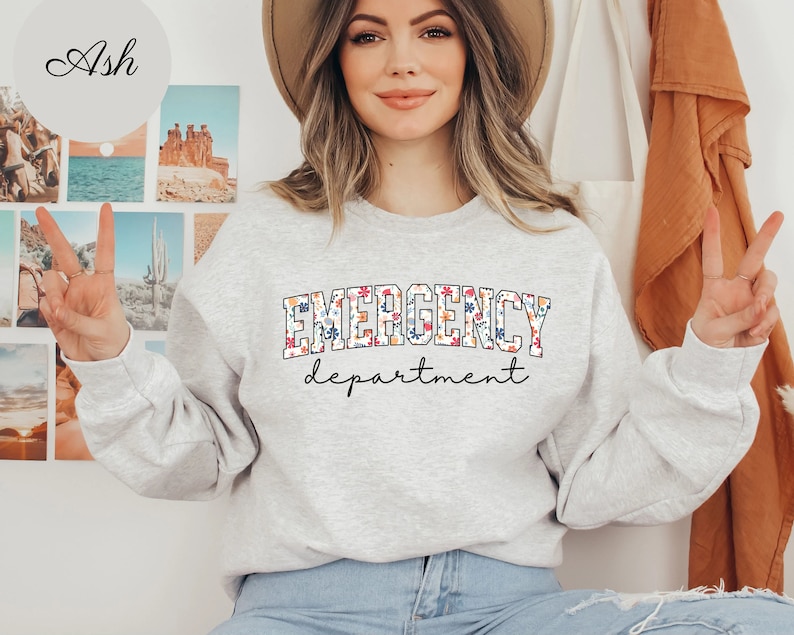 May include: A gray sweatshirt with the text "EMERGENCY department" in white with a floral pattern. The text is in a collegiate font.