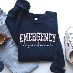 May include: Navy blue sweatshirt with a floral print design that says "EMERGENCY department" in white lettering.