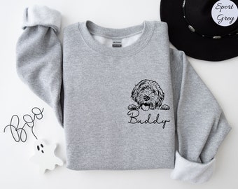 May include: A gray sweatshirt with a black illustration of a dog peeking out from behind a white banner with the name "Buddy" written in black cursive.