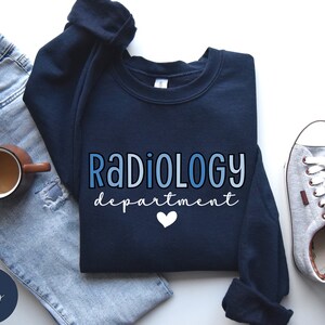 May include: Navy blue sweatshirt with the text "RADIOLOGY department" in blue gradient lettering with a white heart.