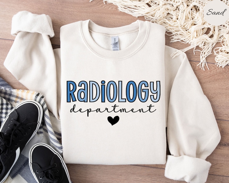 May include: A white sweatshirt with the text "RADIOLOGY department" in blue and black lettering with a black heart below the text.