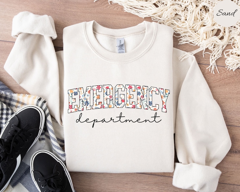 May include: A white sweatshirt with a floral print design that says "EMERGENCY department" in black text.