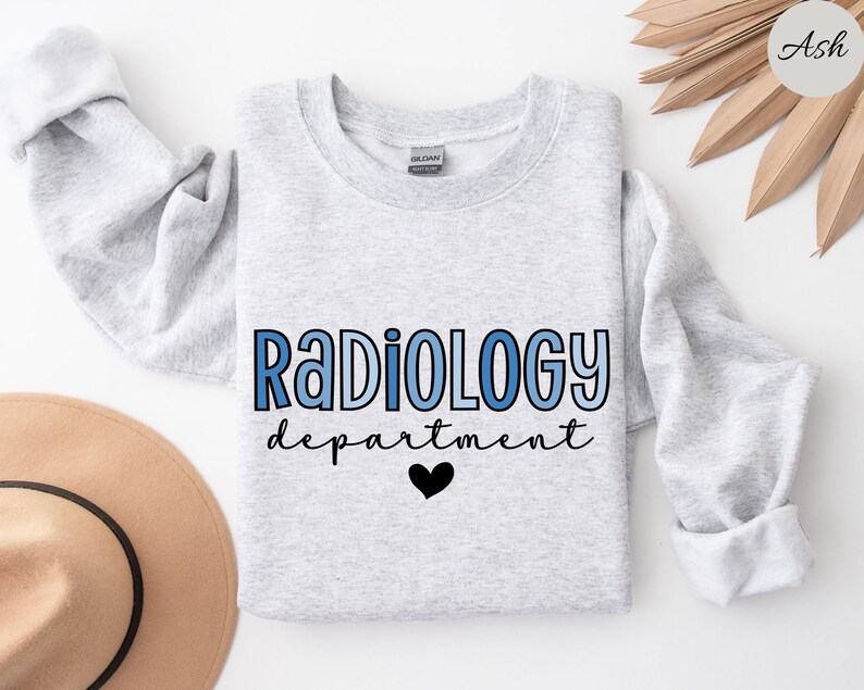 May include: A gray sweatshirt with the text "Radiology department" in blue and black lettering with a small black heart. The sweatshirt is on a white background.