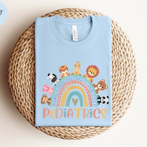May include: Light blue t-shirt with a rainbow and animals, the text "PEDIATRICS" is below the rainbow.
