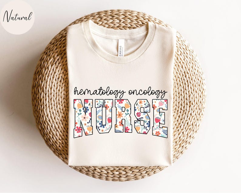 Puede incluir: Una camiseta blanca con un dise&ntilde;o floral que dice "hematology oncology nurse".