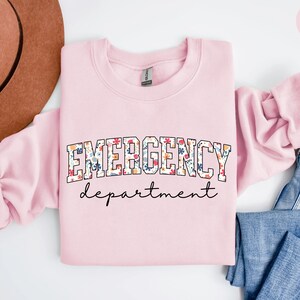 May include: Light pink sweatshirt with the text "EMERGENCY department" in a floral print.