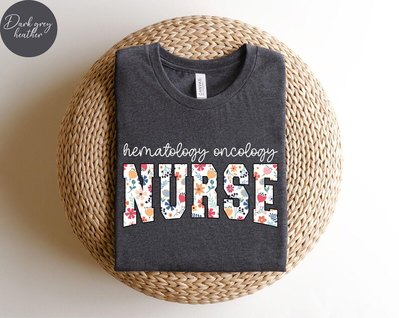 Puede incluir: Camiseta de color gris oscuro jaspeado con un dise&ntilde;o floral que dice "hematology oncology nurse".