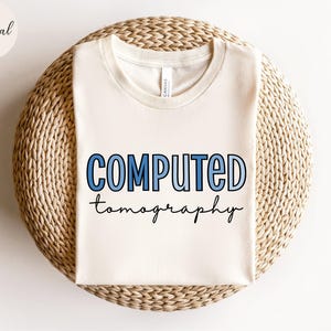 May include: A white t-shirt with the text "COMPUTED tomography" in blue and black lettering.