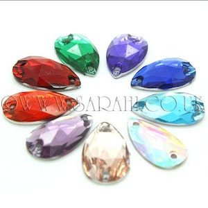 May include: A collection of nine teardrop-shaped faceted crystals in various colors including red, green, purple, blue, light blue, and clear, arranged in a circle. Each crystal features two small holes for sewing. The text WWW.SARAHI.CO.UK is visible.