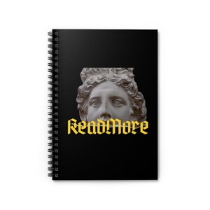 Könnte beinhalten: Ein schwarzes Spiralnotizbuch mit einem Bild einer weißen Marmorbüste und dem Text "Read More" in Gelb.