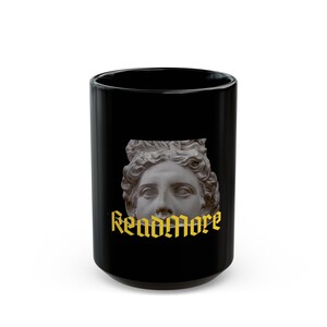 Könnte beinhalten: Schwarze Keramiktasse mit einer weißen Büste einer Frau und dem Text "Read More" in goldenen Buchstaben.