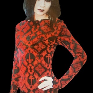 May include: A red and black long-sleeved shirt with a gothic-inspired pattern featuring repeating crosses and ornate designs.