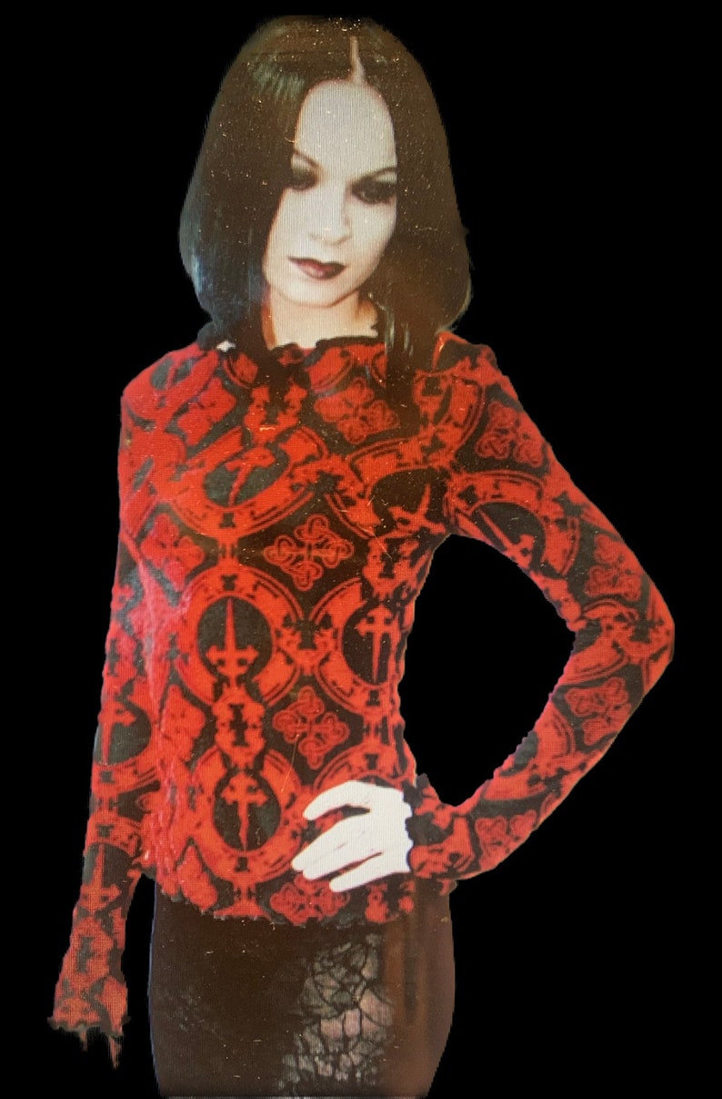 May include: A red and black long-sleeved shirt with a gothic-inspired pattern featuring repeating crosses and ornate designs.