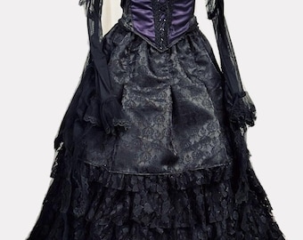 Puede incluir: Un vestido de estilo gótico negro y morado con un corpiño de encaje y una falda de capas. El vestido tiene mangas largas con detalles de encaje y una cintura ajustada.
