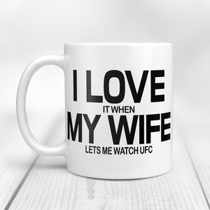 Pode incluir: Caneca de caf&eacute; de cer&acirc;mica branca com texto preto que diz "Eu amo quando minha esposa me deixa assistir UFC".