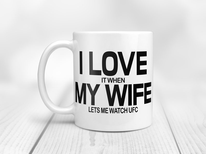 Pode incluir: Caneca de caf&eacute; de cer&acirc;mica branca com texto preto que diz "Eu amo quando minha esposa me deixa assistir UFC".