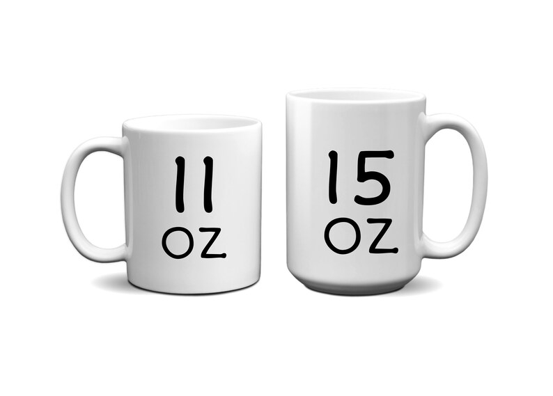 May include: Two white ceramic mugs with black lettering. The smaller mug says "11 oz" and the larger mug says "15 oz".