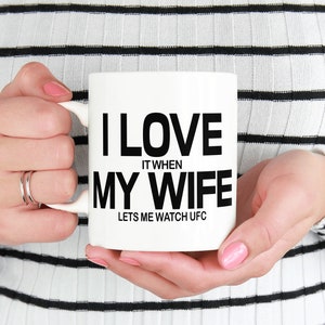 Pode incluir: Caneca de cer&acirc;mica branca com texto preto que diz "Eu amo quando minha esposa me deixa assistir UFC".