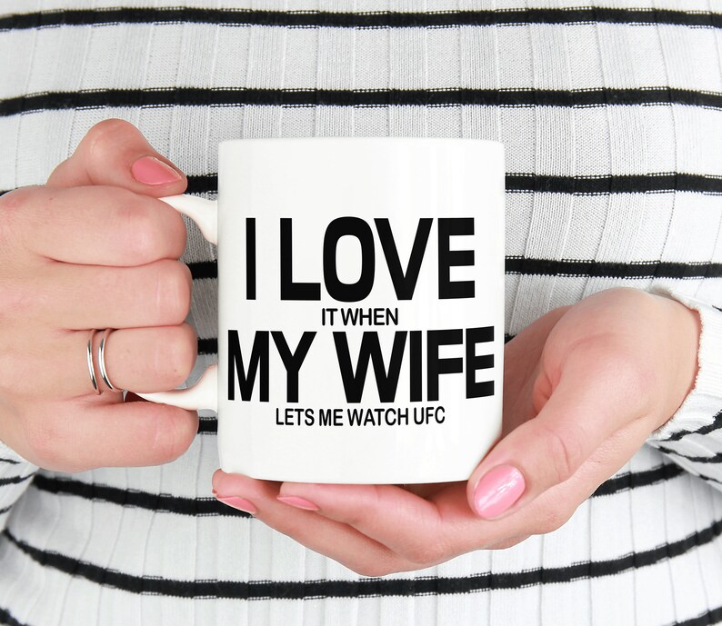 Pode incluir: Caneca de cer&acirc;mica branca com texto preto que diz "Eu amo quando minha esposa me deixa assistir UFC".