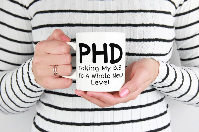 Puede incluir: Taza de cer&aacute;mica blanca con texto negro que dice "PHD Taking My B.S. To A Whole New Level"