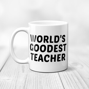 May include: White ceramic mug with the text "WORLD'S GOODEST TEACHER" in bold black letters. The mug has a curved handle and is set against a blurred white background. A gift for teachers.