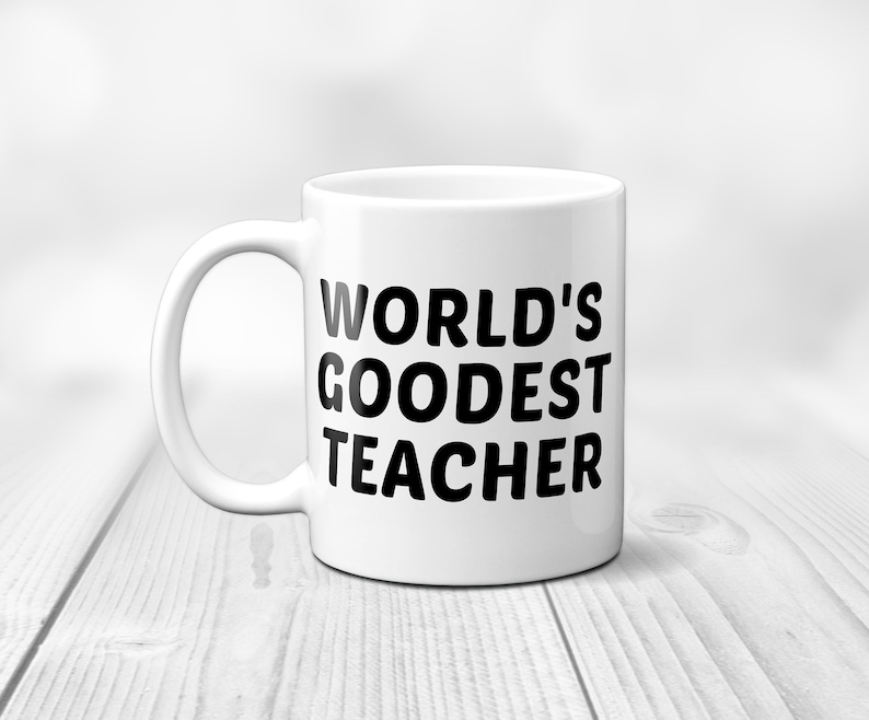 May include: White ceramic mug with the text "WORLD'S GOODEST TEACHER" in bold black letters. The mug has a curved handle and is set against a blurred white background. A gift for teachers.