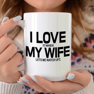 Pode incluir: Caneca de caf&eacute; de cer&acirc;mica branca com texto preto que diz "Eu amo quando minha esposa me deixa assistir UFC".