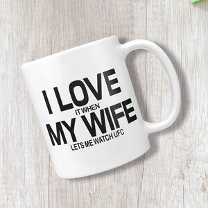 Pode incluir: Caneca de caf&eacute; de cer&acirc;mica branca com texto preto que diz "Eu amo quando minha esposa me deixa assistir UFC".