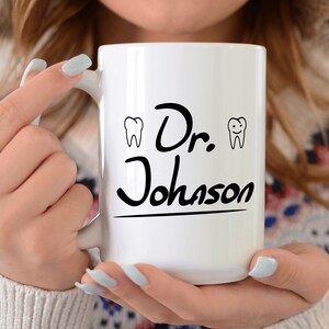 May include: White ceramic coffee mug with black text that reads "Dr. Johnson" and two small black and white tooth illustrations on either side of the text.