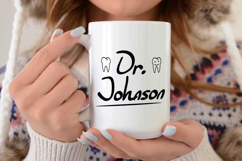 May include: White ceramic coffee mug with black text that reads "Dr. Johnson" and two small black and white tooth illustrations on either side of the text.