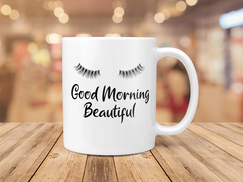 May include: White ceramic coffee mug with a black graphic of closed eyelashes and the text "Good Morning Beautiful".
